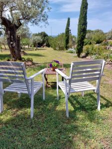 two white benches sitting next to a table with flowers at Arcamyrtus in Alghero