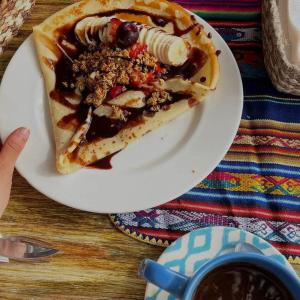 un plato blanco con una rebanada de tarta con frutas y frutos secos en Café Madame, en Puerto López