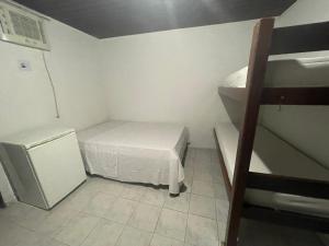um pequeno quarto com uma cama e um frigorífico em Pousada Allamandas Feliz em Salinópolis