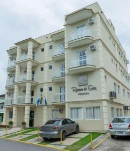 two cars parked in front of a large building at Pousada Reserva do Sahy in Mangaratiba