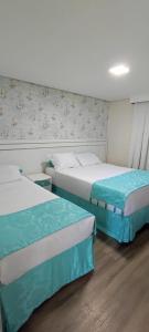 two beds in a hotel room with at Pousada Serrano in Campos do Jordão