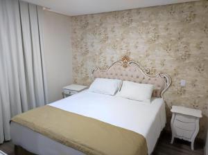 a bedroom with a large white bed and a wall at Pousada Serrano in Campos do Jordão