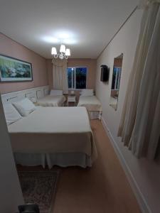 a hotel room with two beds and a window at Pousada Serrano in Campos do Jordão