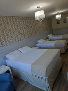 a hotel room with three beds in a room at Pousada Serrano in Campos do Jordão