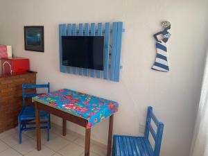 a room with a table and two chairs and a tv at Casa beira mar Jacaraipe. in Serra