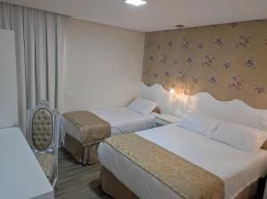 a hotel room with two beds and a chair at Pousada Serrano in Campos do Jordão