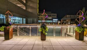 Holiday Inn Lancaster, an IHG Hotel في لانكستر: مجموعة من الأعمدة مع الزهور على الشرفة في الليل