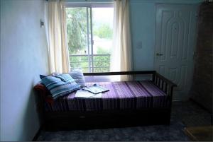 a bed sitting in a room with a window at Departamentos La Gringa in El Bolsón