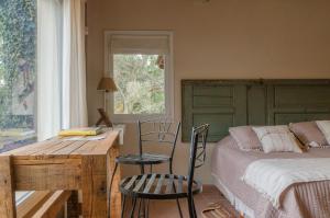 1 dormitorio con 1 cama, mesa y sillas en Entre Sierras B&B en Tandil
