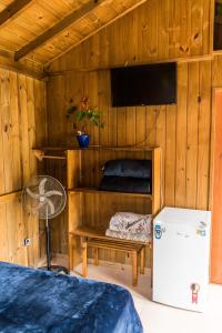 a room with a bed and a tv and a refrigerator at Villa Rosa Cabanas in Guarda do Embaú