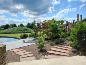 een tuin met een stenen pad en een zwembad bij Le jardin des fagnes in Robertville