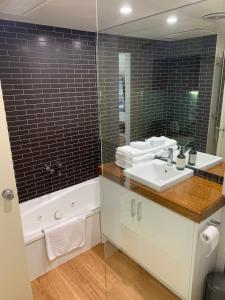 a bathroom with a sink and a tub and a mirror at Lorne Studio Apartment in Lorne