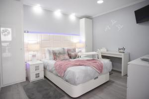 a white bedroom with a white bed and a desk at My way in Azores in Horta