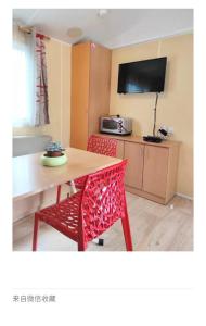 cocina con mesa y silla roja en Camping Quimper, en Quimper