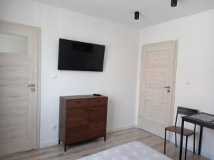 een woonkamer met een tv aan een witte muur bij Dom Hermana in Mrzeżyno