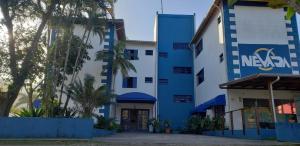 Hotel Nevada Ubatuba في أوباتوبا: مبنى باللون الأزرق والأبيض مع أشجار النخيل