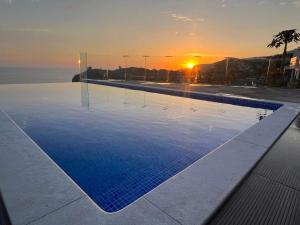 a swimming pool with a sunset in the background at Madeira Sea Sunshine with heated pool in Ribeira Brava