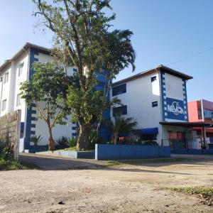 a white and blue building with a tree in front at Hotel Nevada Ubatuba in Ubatuba