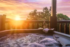 een hot tub op een balkon met zonsondergang bij Bear Time Cabin - Scenic Mountain View, Firepit, Hot Tub, Theater, 4BR 3BA Sleeps 14 in Sevierville