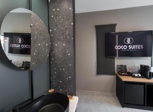 ein Salon mit einem Spiegel und einem schwarzen Stuhl in einem Zimmer in der Unterkunft COCO SUITES in Vasiliki