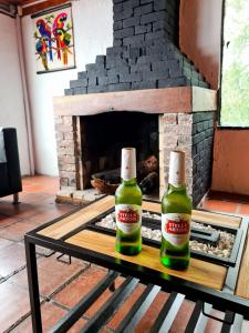 dos botellas de cerveza sentadas en una mesa frente a una chimenea en Hostal San Rafael La Calera, en La Calera