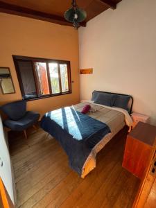 a bedroom with a bed and a chair and a window at Hostel Picus in Itamonte