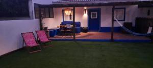 una casa con un cortile con due sedie e un'amaca di Sunrise Monsaraz Blue - Casa com 2 quartos Jardim a Monsaraz