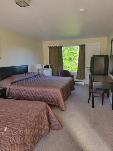 a hotel room with two beds and a desk and a window at Gateway Motel in Gananoque