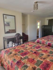 a bedroom with a bed and a table and a desk at Gateway Motel in Gananoque