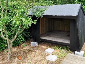 a black dog house with a porch in a garden at 6 person holiday home in Struer in Remmer Strand