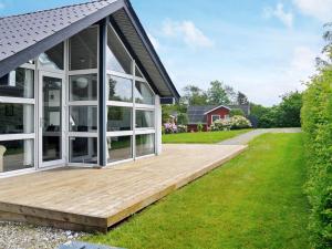 a house with a wooden deck in the yard at 6 person holiday home in Struer in Remmer Strand