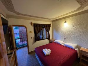 a hotel room with a red bed and a window at Posada don Miguel in Panajachel