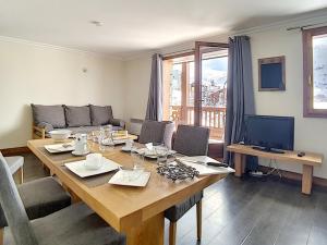 a living room with a wooden table and a television at Appartement rénové proche pistes avec Sauna, Hammam et WIFI - FR-1-344-788 in Levassaix