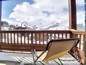a chair sitting on a porch with a snow covered mountain at Appartement rénové proche pistes avec Sauna, Hammam et WIFI - FR-1-344-788 in Levassaix