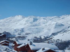 a snow covered mountain with a red building in the foreground at Appartement de standing rénové aux Belleville avec balcon, accès pistes, WiFi, sauna et hammam - FR-1-344-808 in Levassaix