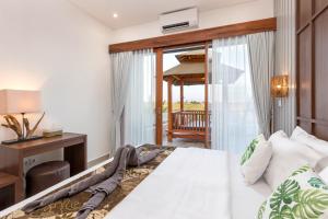 a bedroom with a bed and a desk and a window at Vin Villa Canggu 3 BR with private pool in Canggu +15 photos