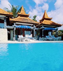 a pool with chairs and umbrellas next to a resort at Soul Lodge Villa Lovina in Banjar