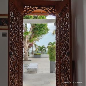 an ornate wooden doorway to a patio with palm trees at Soul Lodge Villa Lovina in Banjar