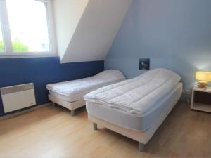 1 dormitorio con 2 camas y pared azul en Appartement La Forêt-Fouesnant, 3 pièces, 4 personnes - FR-1-481-121, en La Forêt-Fouesnant