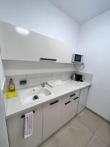 eine weiße Küche mit einer Spüle und einer Mikrowelle in der Unterkunft Dream in the Desert in Beʼer Ora