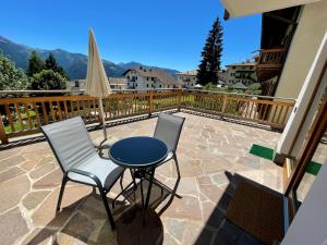 a patio with two chairs and a table and a umbrella at Casa Fabiolin in Daiano
