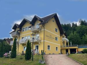 un gran edificio amarillo con balcones y árboles en Seebrise Velden - only 500 meter from lake!, en Velden am Wörthersee
