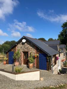 a small house with blue doors and potted plants at Ash Tree in Vire