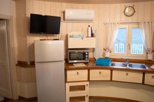 a kitchen with a white refrigerator and a microwave at Nel verde del Villaggio - Casetta Celeste in Gonnesa