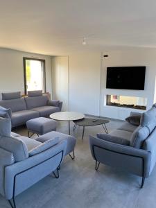 a living room with couches and tables and a flat screen tv at La Villa Métairie in Locmaria