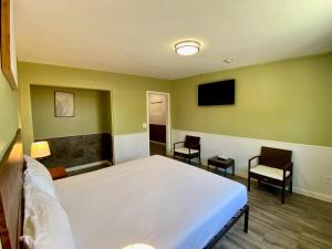 a bedroom with a bed and a tv and chairs at Europa Inn & Suites in Desert Hot Springs