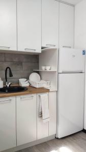 La cuisine est équipée de placards blancs et d'un réfrigérateur blanc. dans l'établissement Apartment on Panfilova 114, à Almaty