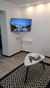 a living room with a table and a tv on a wall at Apartment on Panfilova 114 in Almaty