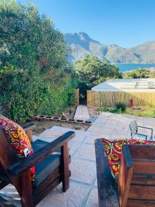 a patio with two wooden benches and mountains in the background at BEAUTIFUL VIEW Garden Apartment in Cape Town