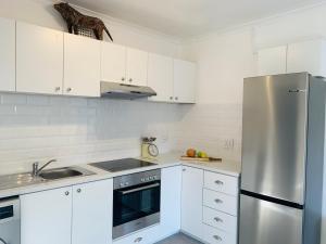 cocina con armarios blancos y nevera de acero inoxidable en BEAUTIFUL VIEW Garden Apartment en Ciudad del Cabo